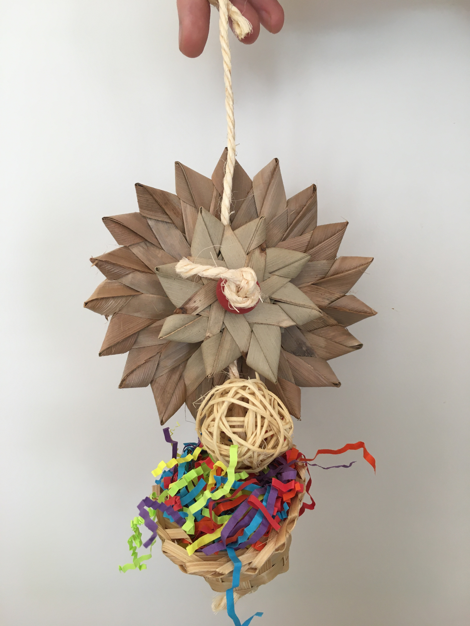flower made from palm leaf on top of a wicker basket stuffed with shredded paper