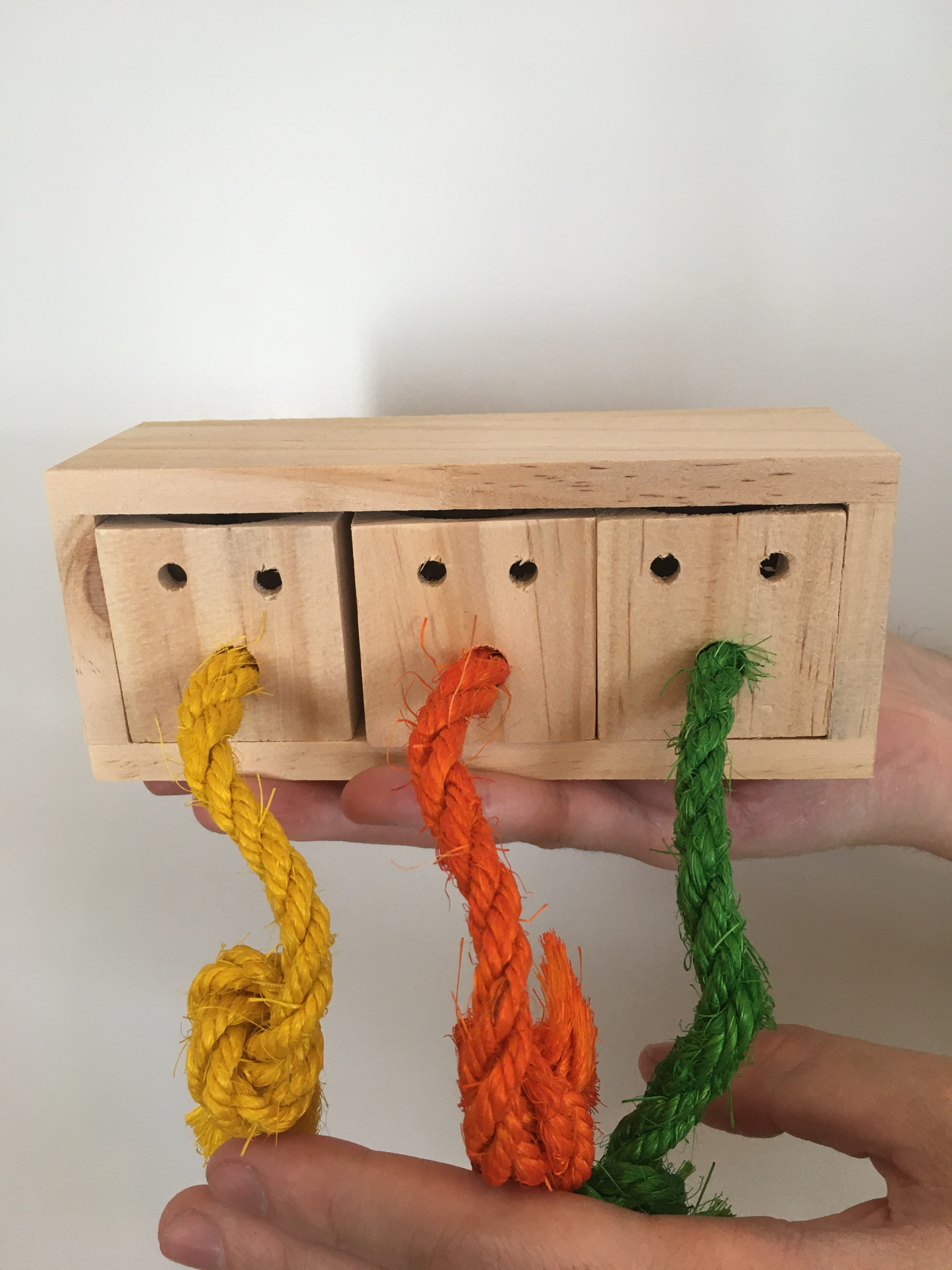 a wooden block with cops and colourful ropes to pull on, natural position.